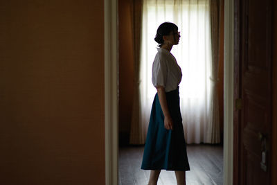 Side view of thoughtful young woman standing at home