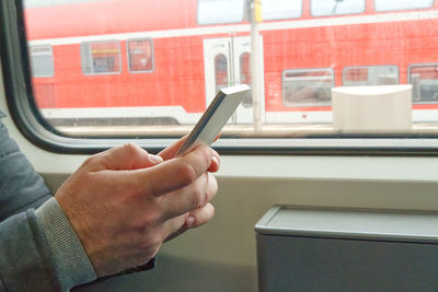 Cropped hand of man using mobile phone in train