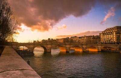Bridge crossing river in paris city during sunset.