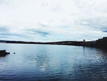 Scenic view of river against cloudy sky