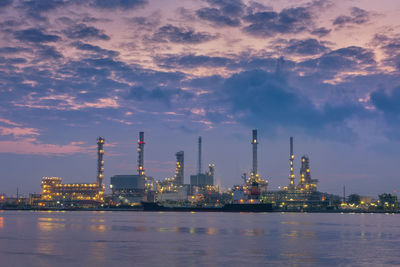 Illuminated factory against sky during sunset