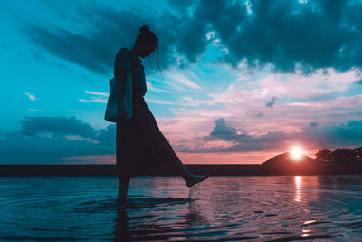 Silhouette man standing by sea against sky during sunset