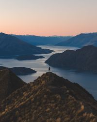 Person on rock against lake during sunset