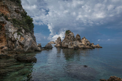 Rock formation in sea against sky