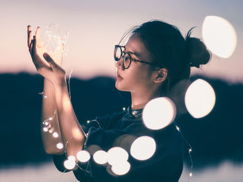 Portrait of young woman holding eyeglasses