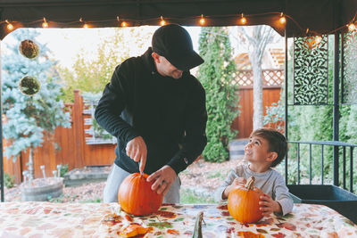 Father and son cutting pumpkin on table