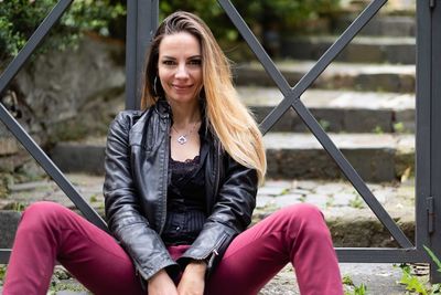 Portrait of smiling woman sitting against gate