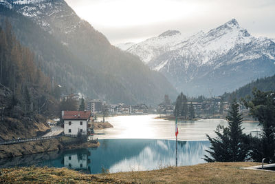 Scenic view of lake by buildings against sky during winter