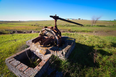 Old rusty metallic structure on field against sky