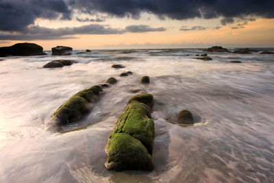 Scenic view of sea against cloudy sky during sunset