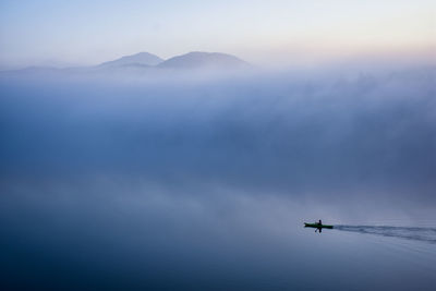 High angle view of silhouette person in boat on lake against sky