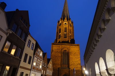 Low angle view of illuminated buildings against clear blue sky