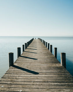 Wooden pier on sea against clear sky