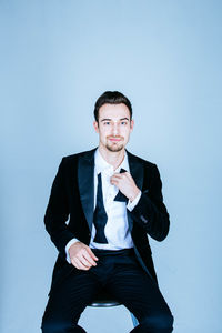 Portrait of businessman gesturing against blue background