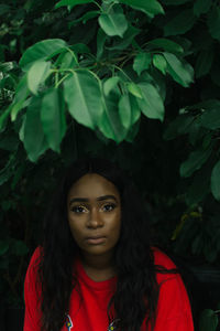 Portrait of confident young woman against trees in park