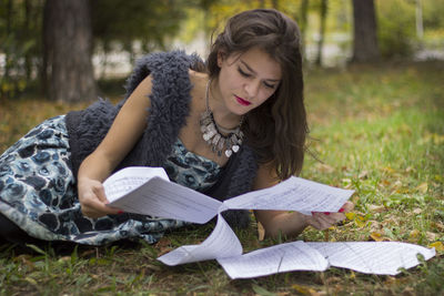 Beautiful young woman reading papers on field