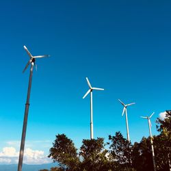 Low angle view of wind turbine against clear blue sky