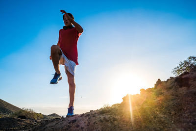 Young man running on road against sky during sunset