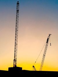 Low angle view of silhouette crane against sky during sunset