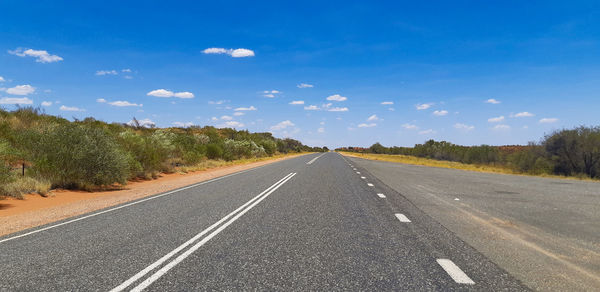 Empty road by trees against sky