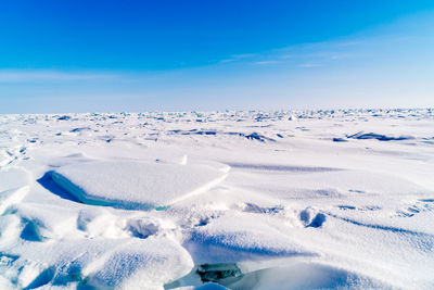 Scenic view of snow covered land against blue sky