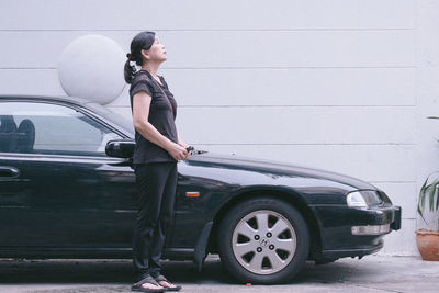 Side view of woman standing by car