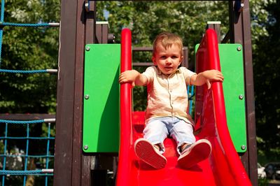 Little toddler playing on the playground and sitting on a slide