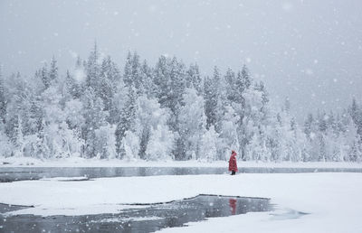 A woman with red clothes standing on the snow covered landscape