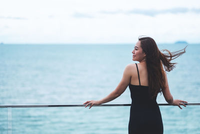 Woman standing in sea against sky