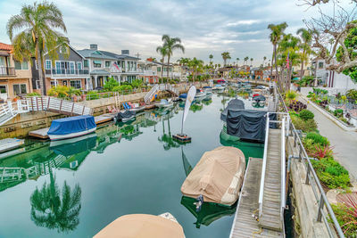 Boats moored in swimming pool by buildings against sky