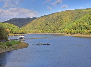 Scenic view of river by mountains against sky