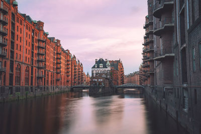 View of building by canal during sunset