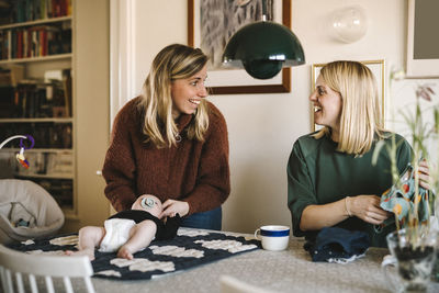 Smiling mothers taking care of newborn baby at home