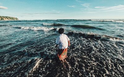 Rear view of woman standing in sea