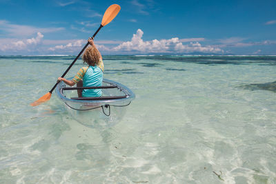 Rear view of woman in inflatable boat on sea against sky