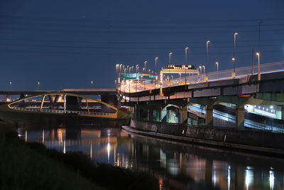 Illuminated bridge over river against sky at night