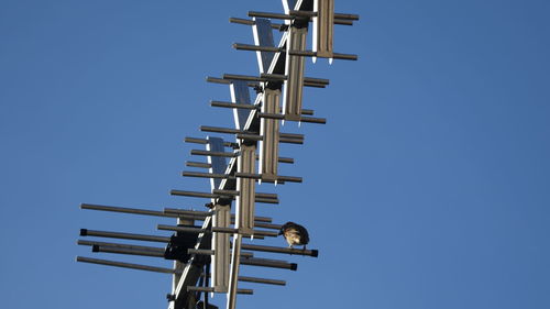 Low angle view of communications tower against clear blue sky