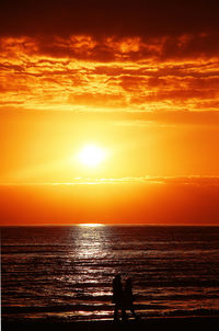 Scenic view of sea against dramatic sky during sunset