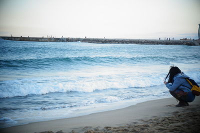 Rear view of woman looking at sea against sky