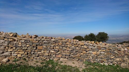 Retaining stone wall on mountain against blue sky