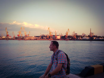 Man standing by sea against sky during sunset