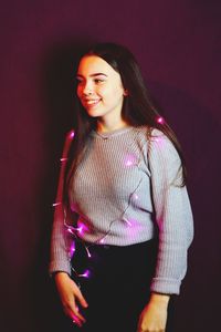 Beautiful young woman with pink string lights