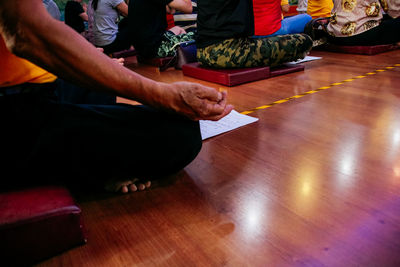 Low section of people sitting on hardwood floor