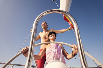 Couple standing by steering wheel on boat at sea