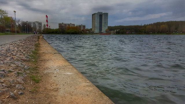 sky, water, architecture, building exterior, built structure, cloud - sky, the way forward, river, city, cloudy, cloud, diminishing perspective, waterfront, transportation, incidental people, rippled, outdoors, vanishing point, nature, day