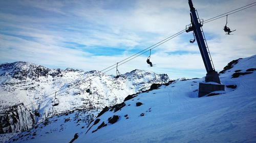 Low angle view of ski lift over snowcapped mountains against sky