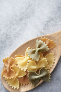 Close-up of farfalle in wooden spoon on marble