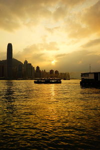 Scenic view of buildings by sea against sky during sunset