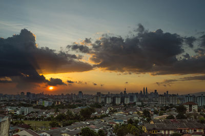 Cityscape against cloudy sky during sunset