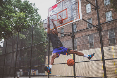 Young man scoring goal at basketball court